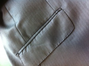 Ribbed pocket jets done by machine. The piping strip should be thin, pressed open not have a ridge.