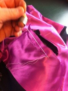 This picture shows me hand basting and fixing the lining into the inner coat armhole.